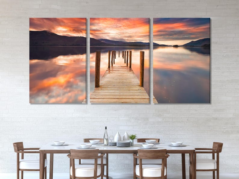 Three-panel lake sunset artwork with a wooden jetty extending into calm water and reflected clouds