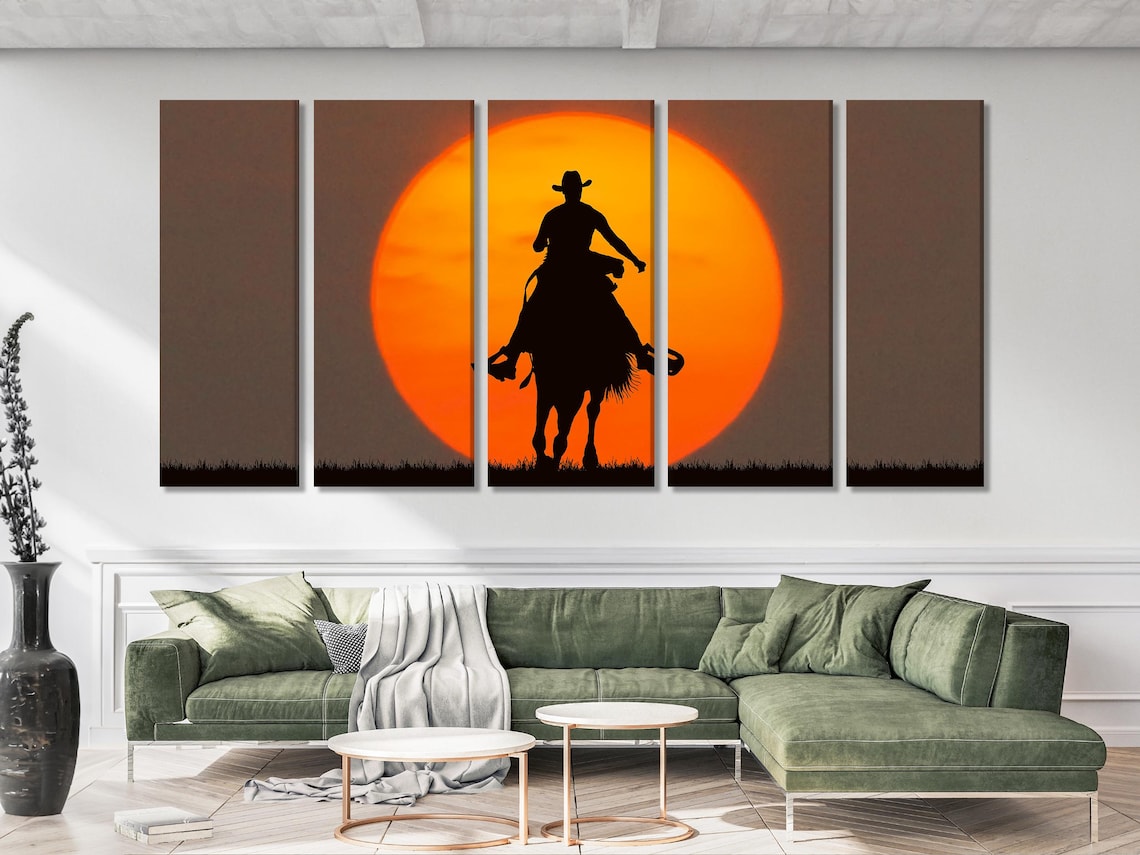 Black cowboy riding a horse silhouette beneath a glowing orange sun with dark grass detail view