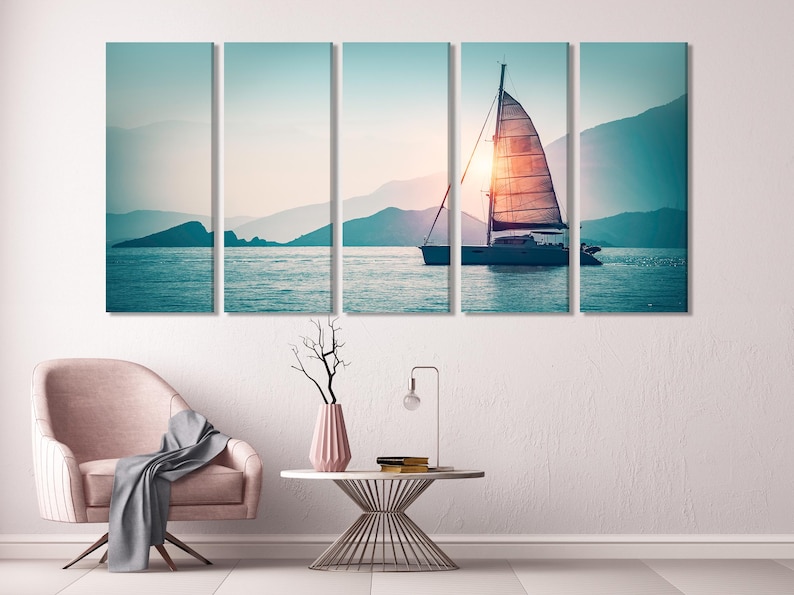 Sunset sailboat seascape with warm glow on sails, calm blue water and distant mountains