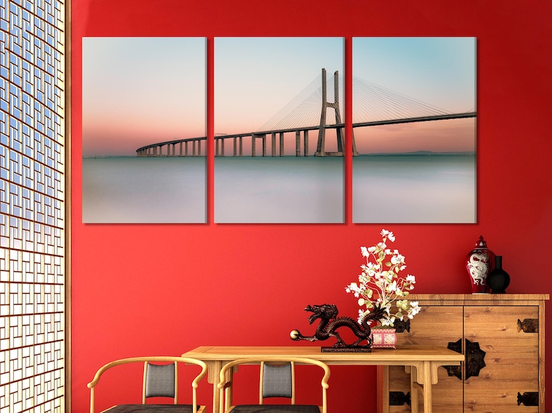Sunset cable-stayed bridge spanning calm water with pastel sky gradients