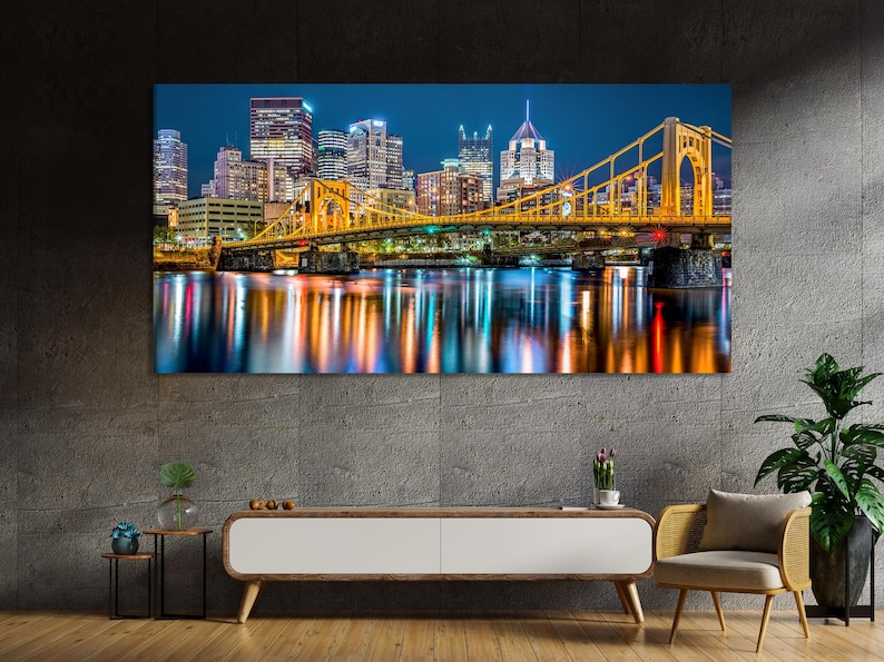 Night city skyline with a brightly lit golden bridge and glowing reflections in a river