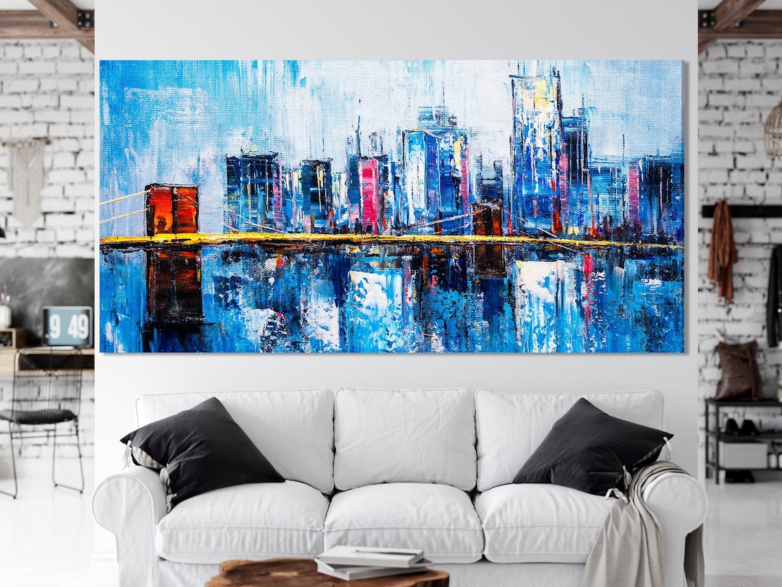 Living room mockup with teal sofa and three-panel blue cityscape wall art above it