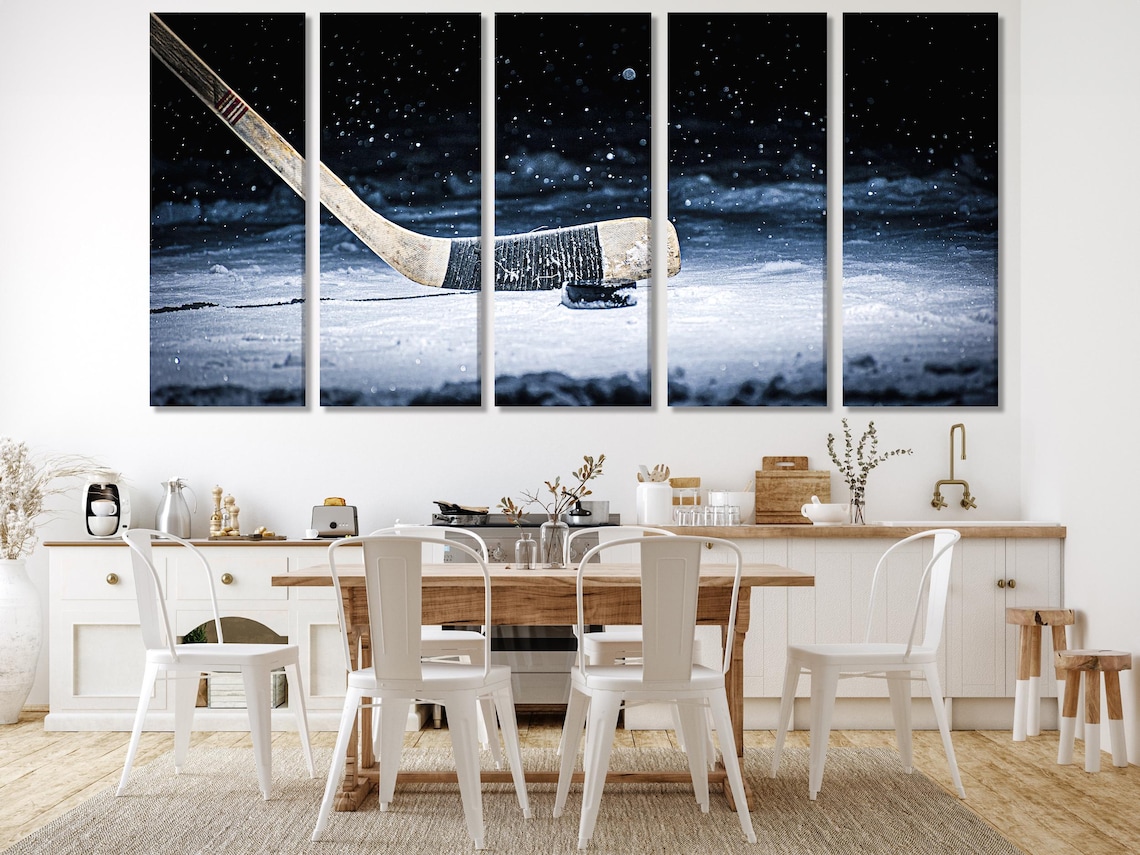 Snowy ice hockey scene with a hockey stick angled across the frame and a puck on bright ice, falling snow in a dark night sky detail view
