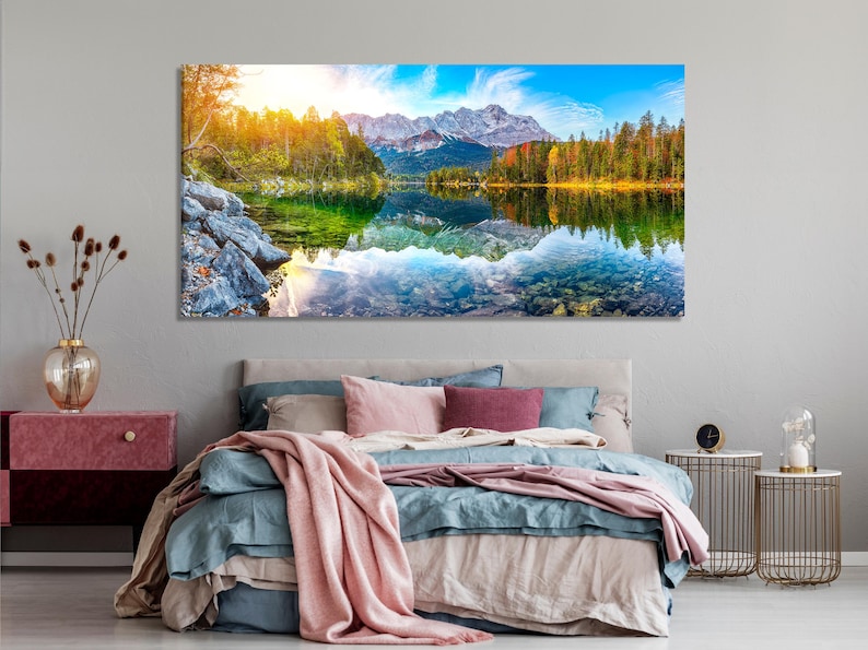 Panoramic mountain lake landscape with rocky shoreline, reflected trees, blue peaks and autumn colours