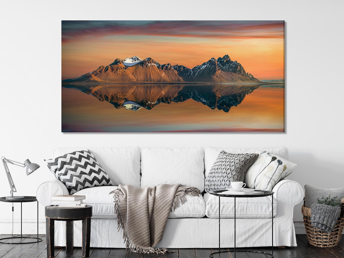 Dining table scene with a five-panel sunset mountain artwork on a white brick wall