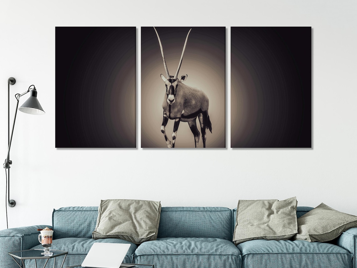 A black-and-white oryx stands centred against a dark, vignetted background, with soft light rays and a crisp, high-contrast animal portrait style