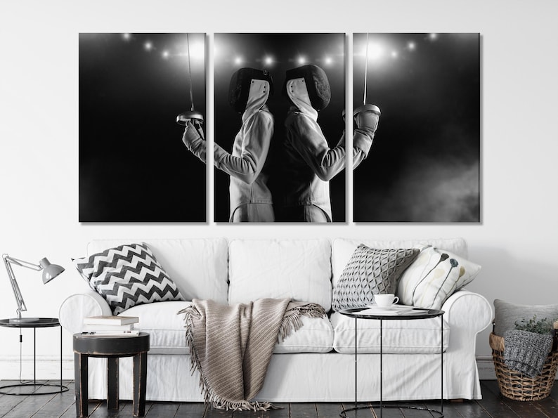 A black-and-white, high-contrast image shows two fencers facing each other in a duel pose, framed by dark negative space and bright spotlight effects