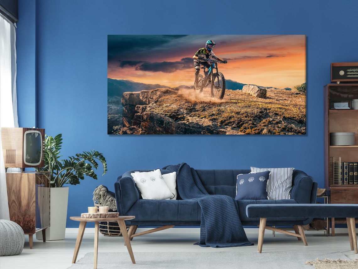 Mountain biker sunset wall artwork displayed above a blue sofa in a living room