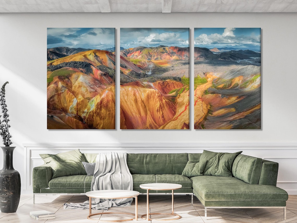 Mountain landscape artwork above a sofa with teal cushions and neutral decor