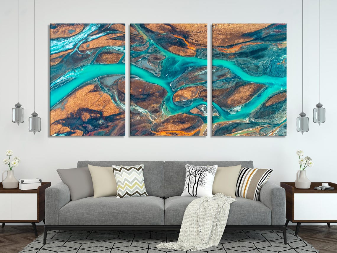 Aerial river delta artwork with winding turquoise water channels over warm brown and dark rocky terrain detail view