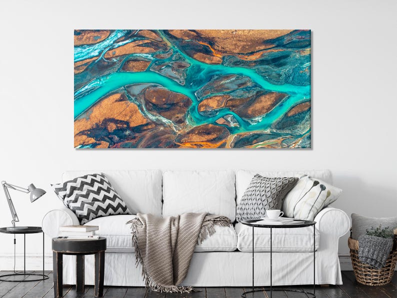 Aerial river delta artwork with winding turquoise water channels over warm brown and dark rocky terrain