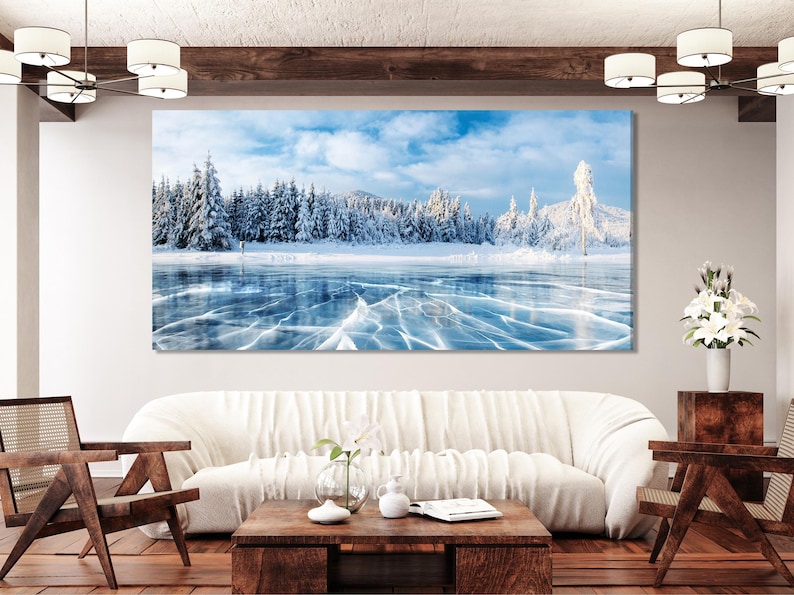 Winter landscape of a frozen lake with icy crack lines and snow-covered pine trees under a pale blue sky