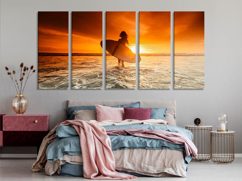 Sunset beach scene with a silhouetted surfer holding a surfboard in front of golden ocean waves