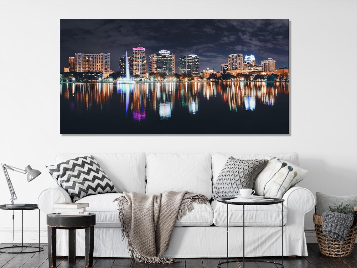 Three-panel night cityscape with illuminated buildings and reflections on dark lake water detail view