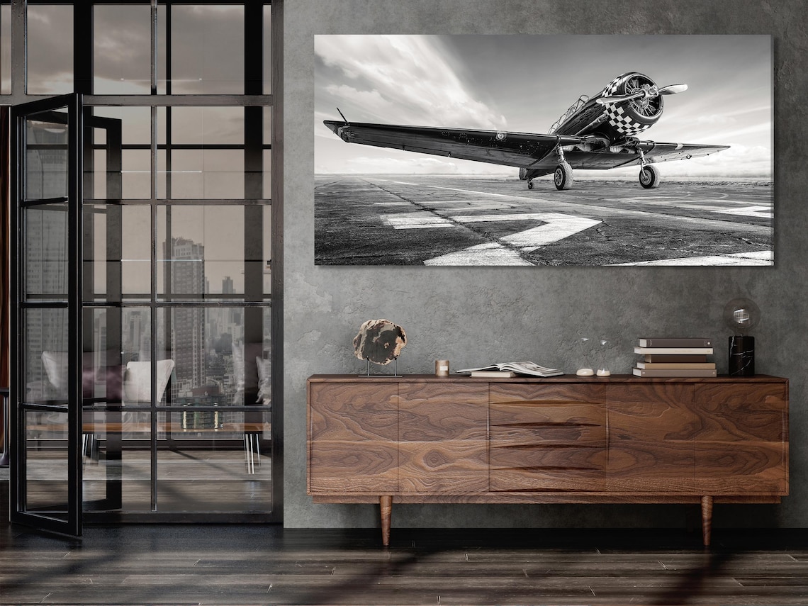 Living room mockup with a wall displaying black and white multi-panel airplane runway artwork above a sofa
