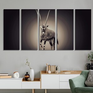 May include: A split canvas wall art print featuring a black and white image of an oryx, an antelope with long, curved horns, standing in a desert landscape.