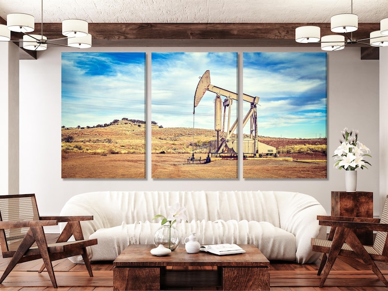 Oil pump jack on a desert oilfield under a bright blue, cloud-filled sky