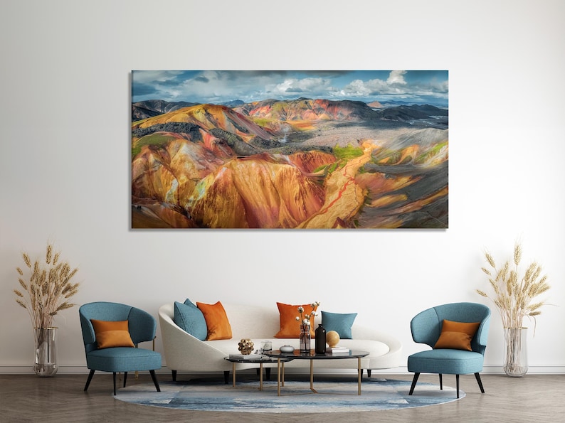 Panoramic mountain landscape with golden and rust ridges under a deep blue, cloudy sky