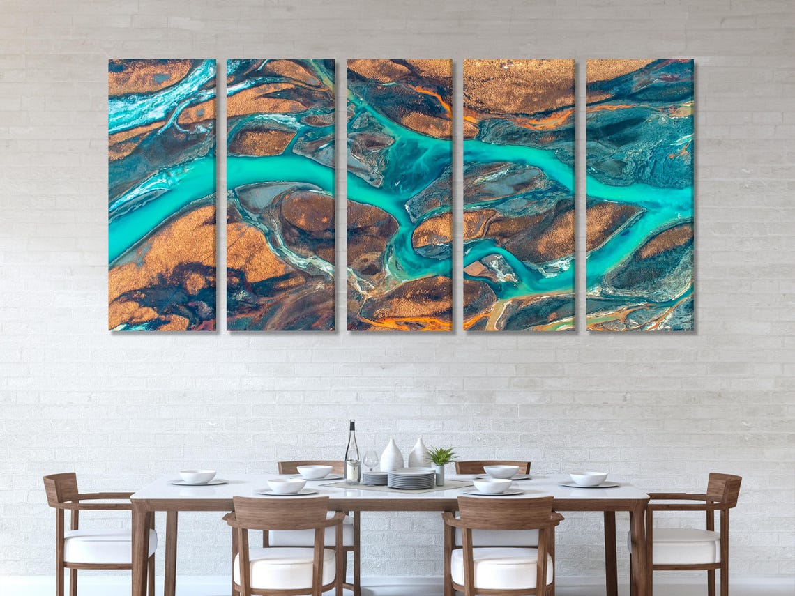 Aerial river delta artwork with winding turquoise water channels over warm brown and dark rocky terrain detail view