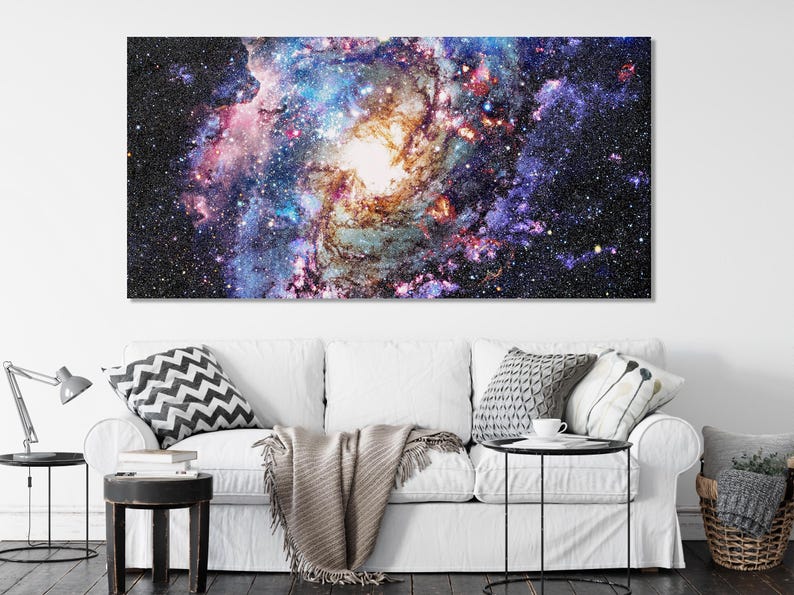 A star-filled nebula scene swirls in deep black space, with bright white cores and colourful purple, blue, pink and orange clouds across the