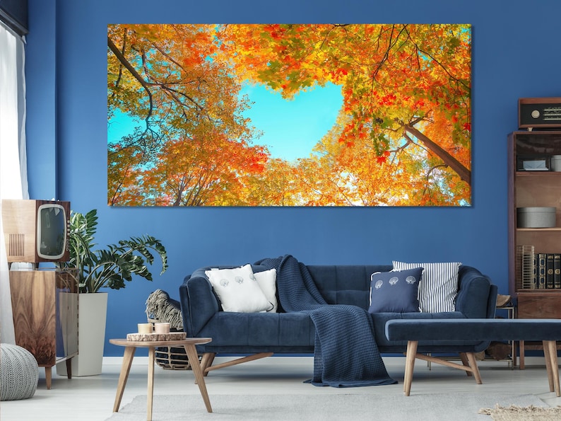 Autumn forest canopy with tree branches and dense fall leaves framing a bright blue sky