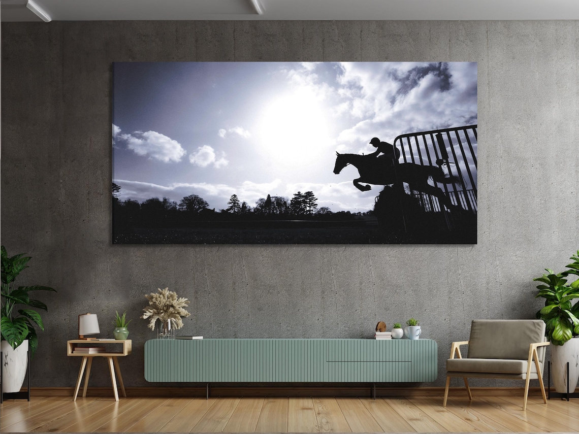 Black silhouette of a jumping horse and rider against a cloudy monochrome sky detail view