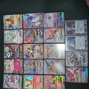 Puede incluir: Una colección de cartas coleccionables de Pokémon, con varios personajes y diseños. Las cartas muestran colores vibrantes, efectos holográficos e ilustraciones detalladas. Las cartas están dispuestas sobre una superficie oscura.