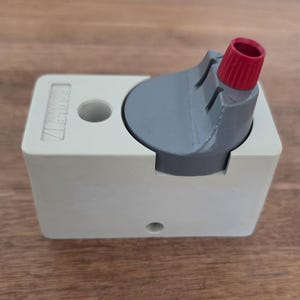 May include: A light beige plastic device with a gray top and a red nozzle. The device has the text "EAGLE 17" printed on the side. The device is sitting on a wooden surface.
