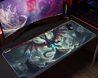 May include: A black dragon with red wings and glowing blue eyes is featured on a dark grey and blue gaming mouse mat with a rainbow-coloured border. The mouse mat is on a wooden surface.