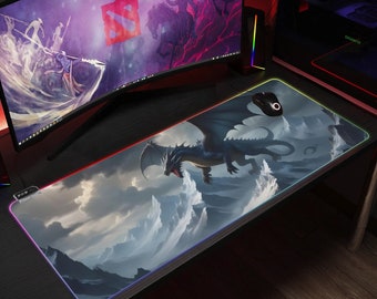May include: A large, blue dragon with wings outstretched flies over a cloudy, mountainous landscape. The dragon is depicted on a rectangular mouse mat with a colourful, glowing border.