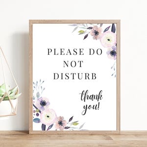 Può includere: Un cartello bianco con un bordo floreale e il testo "Si prega di non disturbare, grazie!" in lettere nere.