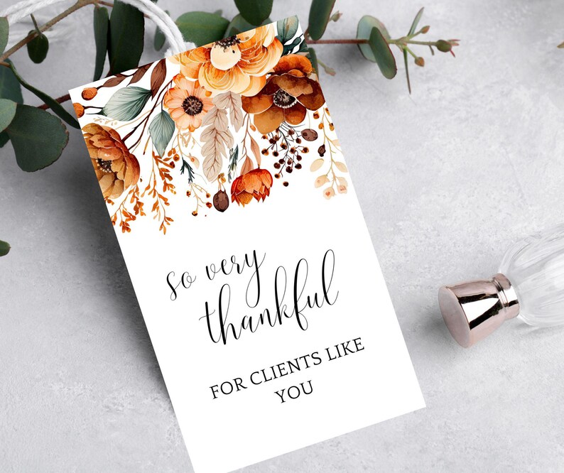 Op de afbeelding: Een witte kaart met een bloemenontwerp in tinten oranje, bruin en groen. De tekst op de kaart luidt "So very thankful for clients like you."