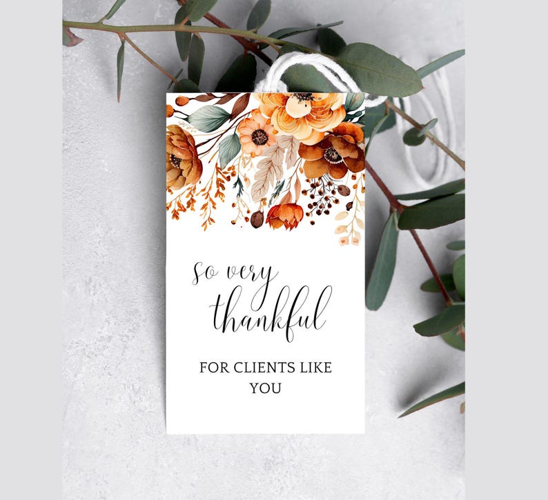 Op de afbeelding: Een wit label met een bloemenontwerp in tinten oranje, bruin en cr&egrave;me. De tekst "So very thankful for clients like you" is in zwart gedrukt.