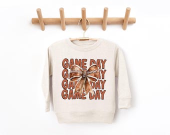 May include: A cream coloured sweatshirt with a brown football bow and the text "GAME DAY" repeated four times.