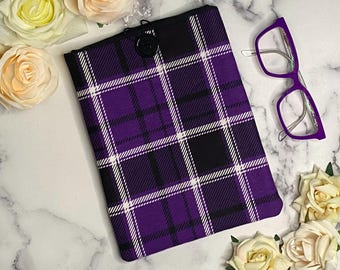 Pode incluir: Capa para tablet de tecido xadrez roxo e preto com fecho de botão branco.