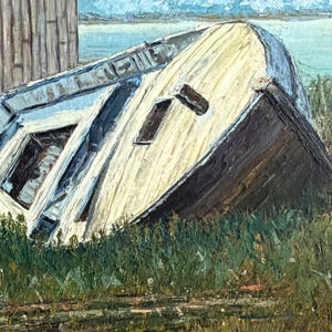 May include: An oil painting depicting a weathered, light-coloured wooden boat resting on its side in a patch of green grass. The vessel features visible planks and dark structural details, positioned near a rustic wooden building by a body of water.