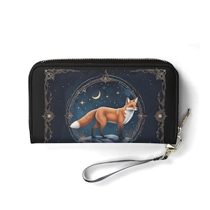 May include: Black wallet with a detailed illustration of a fox under a crescent moon and stars. The fox is in orange, brown, and white against a dark blue background. The wallet has a wrist strap and a gold-coloured zip.