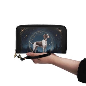 May include: Black wallet with a German Shorthaired Pointer illustration inside a starry circle, set against a dark forest backdrop. The wallet has a wrist strap and a gold-coloured zipper pull.