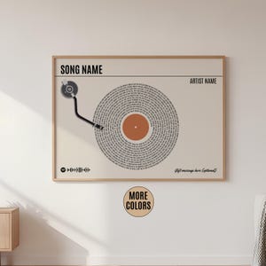 May include: A framed print with a vinyl record design. The record is beige with a brown centre and text forming the grooves. The top has text fields for "Song Name" and "Artist Name". A Spotify code and the words "More Colors" are also visible.