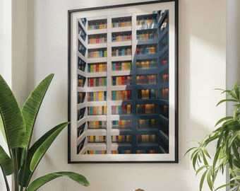 Puede incluir: Un sofá blanco con un cojín marrón se encuentra en una sala de estar con una ventana grande, un armario de madera y una mesa de café con libros y un tazón de dulces. Una impresión enmarcada de un edificio colorido con muchas ventanas cuelga de la pared.