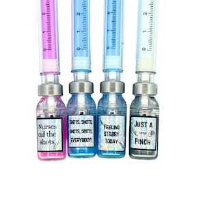 close up of four different vial caps with pen in cap. pink liquid vial says nurses call the shots, blue liquid vial says shots shots shots shots everybody, blue liquid vial says feeling stabby today, gray liquid vial says just a little pinch