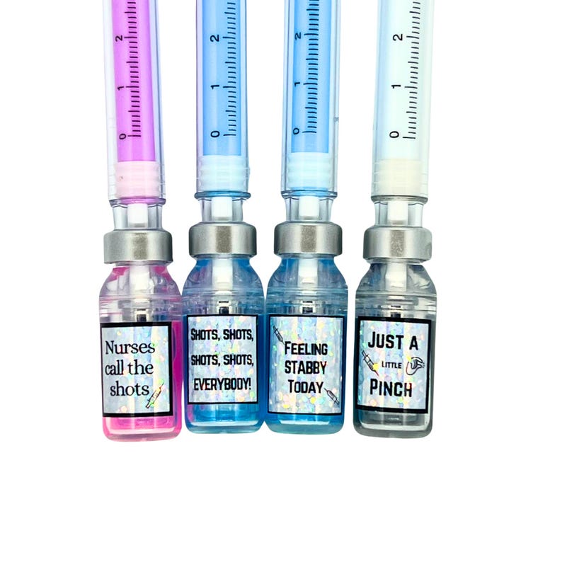close up of four different vial caps with pen in cap. pink liquid vial says nurses call the shots, blue liquid vial says shots shots shots shots everybody, blue liquid vial says feeling stabby today, gray liquid vial says just a little pinch