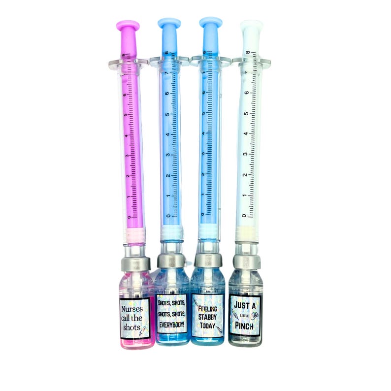 four different pens. pink pen and liquid that says nurses call the shots, blue pen and liquid that says shots shots shots shots everybody, blue pen and liquid that says feeling stabby today, white pen with gray liquid that says just a little pinch