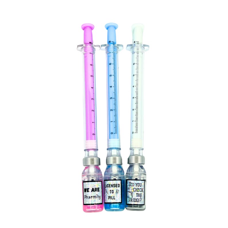 three different pens. pink pen says we are pharmily, blue pen says licensed to pill, white pen with gray liquid cap says did you check the fridge?