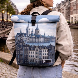May include: A roll-top backpack featuring a cityscape design in shades of blue and gray. The backpack has a black buckle closure and straps. The top portion of the bag depicts a blue sky with white clouds. The lower portion of the bag shows a detailed illustration of buildings.