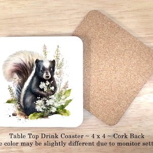 May include: A white ceramic coaster with a watercolor illustration of a black and white skunk with a white flower in its paw. The skunk is surrounded by white flowers and green leaves. The coaster has a cork backing.