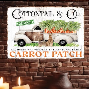 May include: A rustic wooden sign featuring a vintage white truck filled with carrots and greenery. Two rabbits are in front of the truck. The sign reads "COTTONTAIL & Co." and "CARROT PATCH" with the word "ORGANIC" on a green sign.