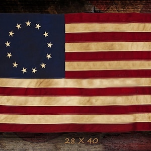 May include: A vintage American flag with 13 stars arranged in a circle on a blue field, and 13 alternating red and white stripes. The flag measures 28 x 40 inches.