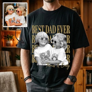 May include: Black t-shirt with the text "BEST DAD EVER" in gold lettering. The shirt features a black and white photo of two children wearing sunglasses. The photo is labeled "Thomas & Emily".