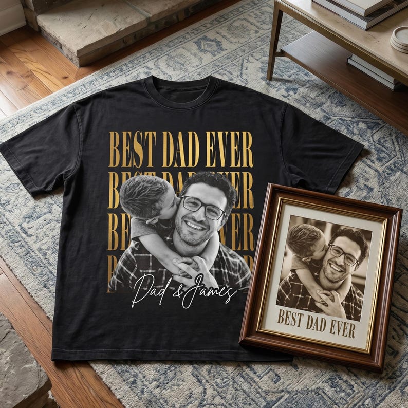 K&ouml;nnte beinhalten: Schwarzes T-Shirt mit goldenem Text "BEST DAD EVER" und einem Sepia-Foto eines Mannes und eines Kindes. Ein gerahmtes Foto mit dem gleichen Bild und Text ist ebenfalls vorhanden.